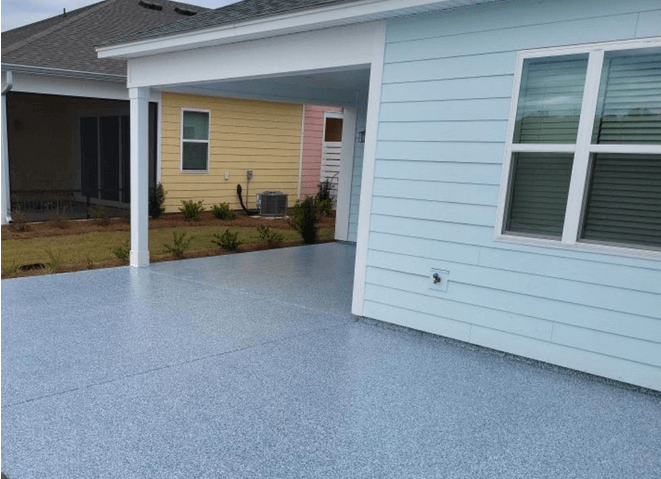 A back concrete patio covered in an epoxy flake coating in a grey color.