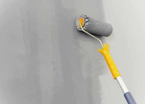 A wall in a home getting a fresh coat of paint in a neutral grey color.